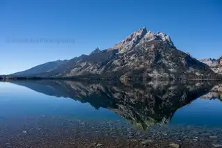 The%20Tetons%20reflect%20in%20the%20perfectly%20still%20water%20of%20Jenny%20Lake.